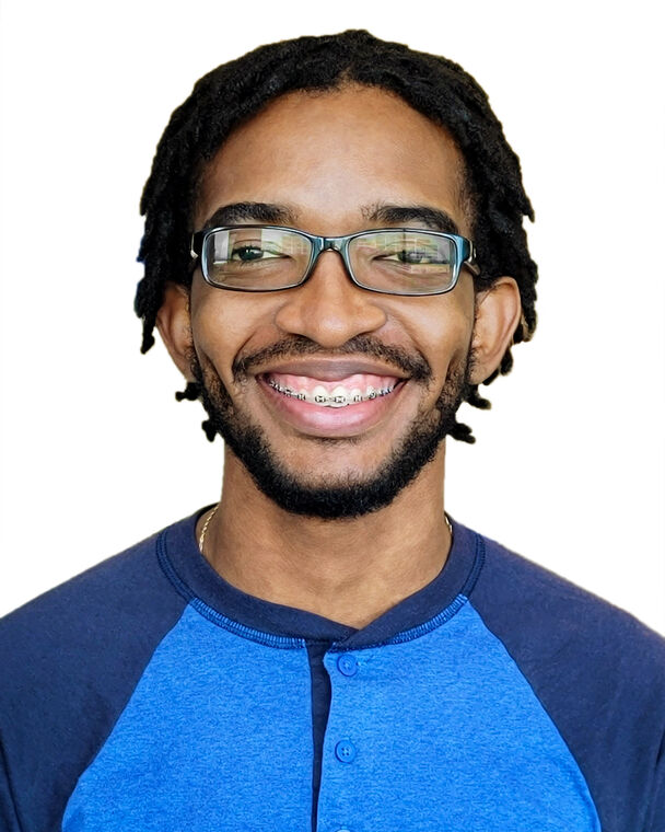 A headshot of Desmond Edwards who is smiling at the camera and wearing glasses and a two-toned blue shirt.