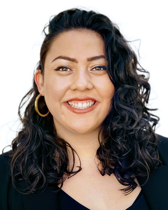 A headshot of Janel Pineda who is smiling at the camera and wearing a black blouse.