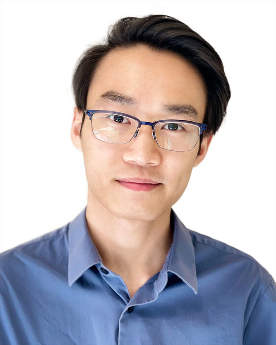 A headshot of Tan Dao who is looking at the camera, wearing a blue collared shirt and glasses.