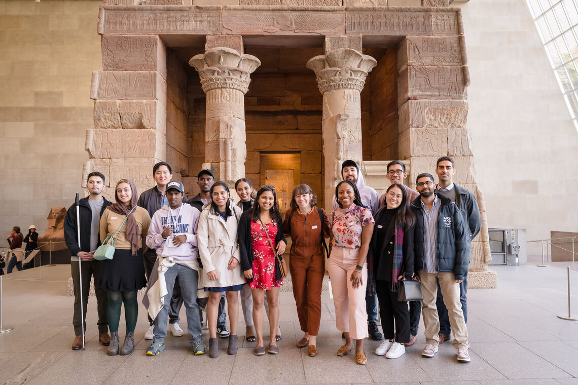 A group photo of Paul & Daisy Soros Fellows at the MET at the Temple of Dendur, an enormous temple that was rebuilt within a huge open room at the MET.