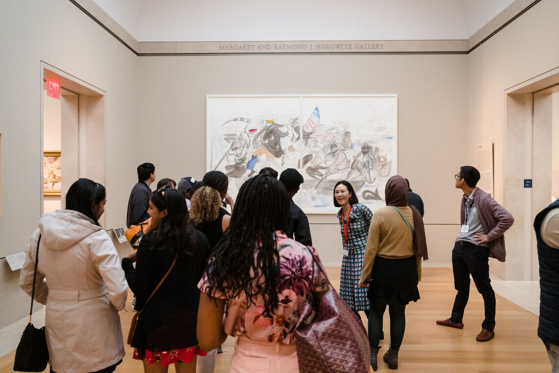 A photo taken of a group of Paul & Daisy Soros Fellows in a gallery at the MET- they are looking at Kara Walker's version of "The Crossing".