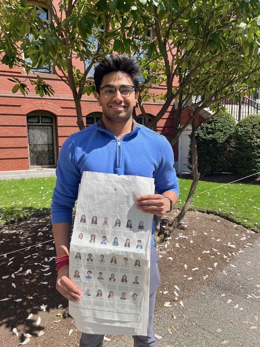 aayush karan standing in front of the harvard museum of natural history and holding the new york times ad