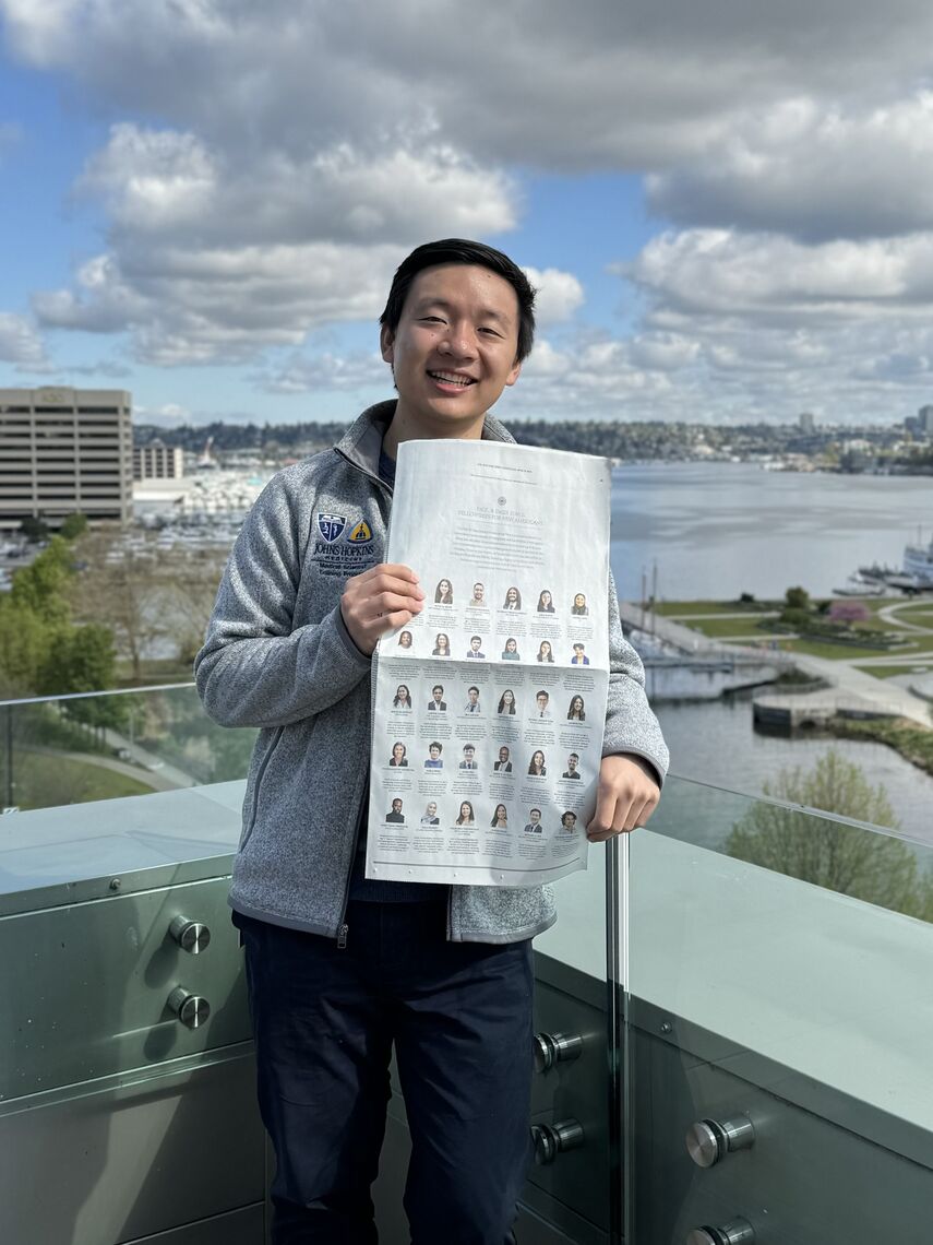 michael xie holding the new york times ad and overlooking lake union from the balcony of the allen institute in seattle where he is currently conducting research