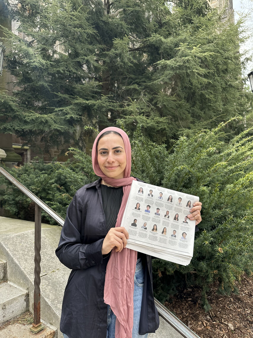 2024 Paul & Daisy Soros Fellow Rana Thabata holding the 2024 New York Times advertisement at the University of Michigan Law School where she attends school.